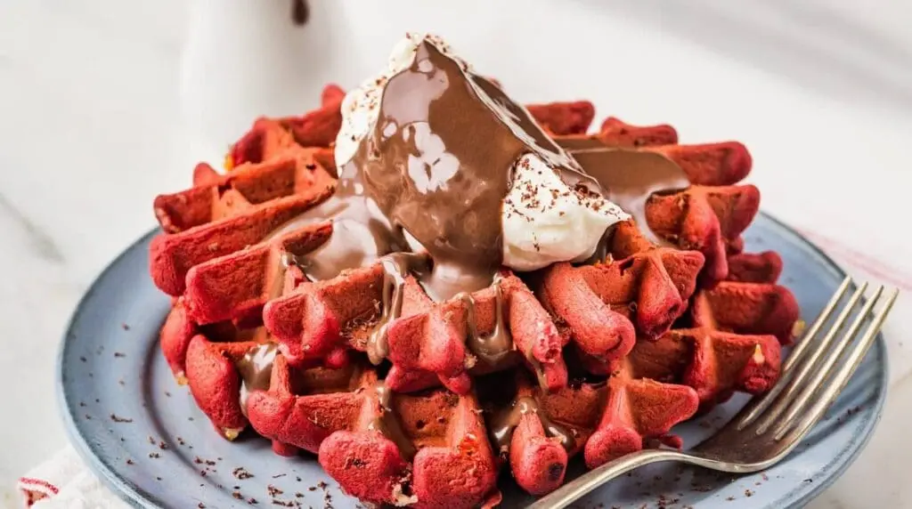 red velvet waffles with whipped cream and chocolate sauce