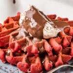 red velvet waffles with whipped cream and chocolate sauce
